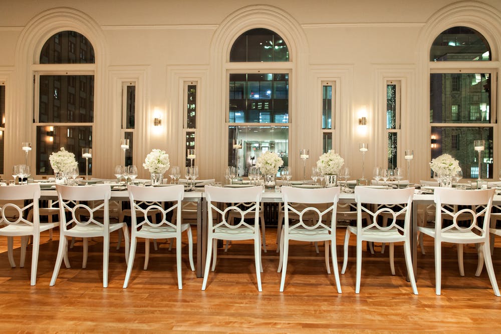 Historic arched windows are the backdrop for a modern white banquet table in the May Room