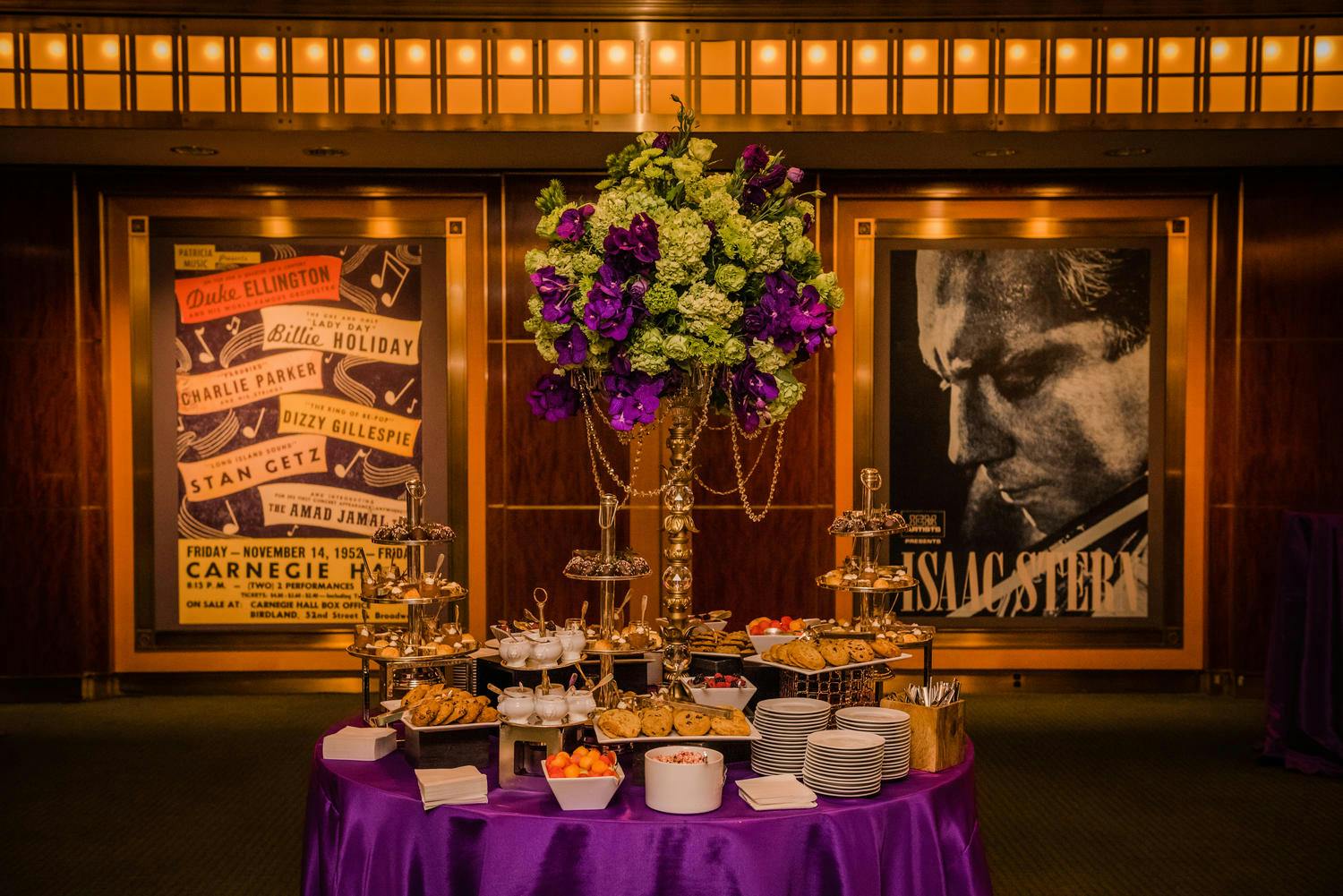 A dessert station with tall florals in the Rohatyn Room; historic concert posters in the background