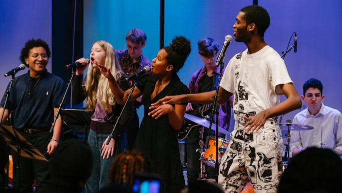 Teen musicians of the Future Music Project Ensemble sing and dance together during a performance.