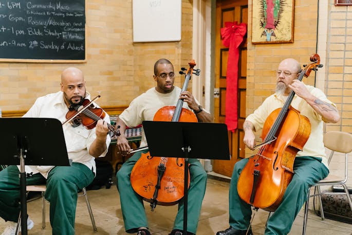 Two men play cello as another plays violin