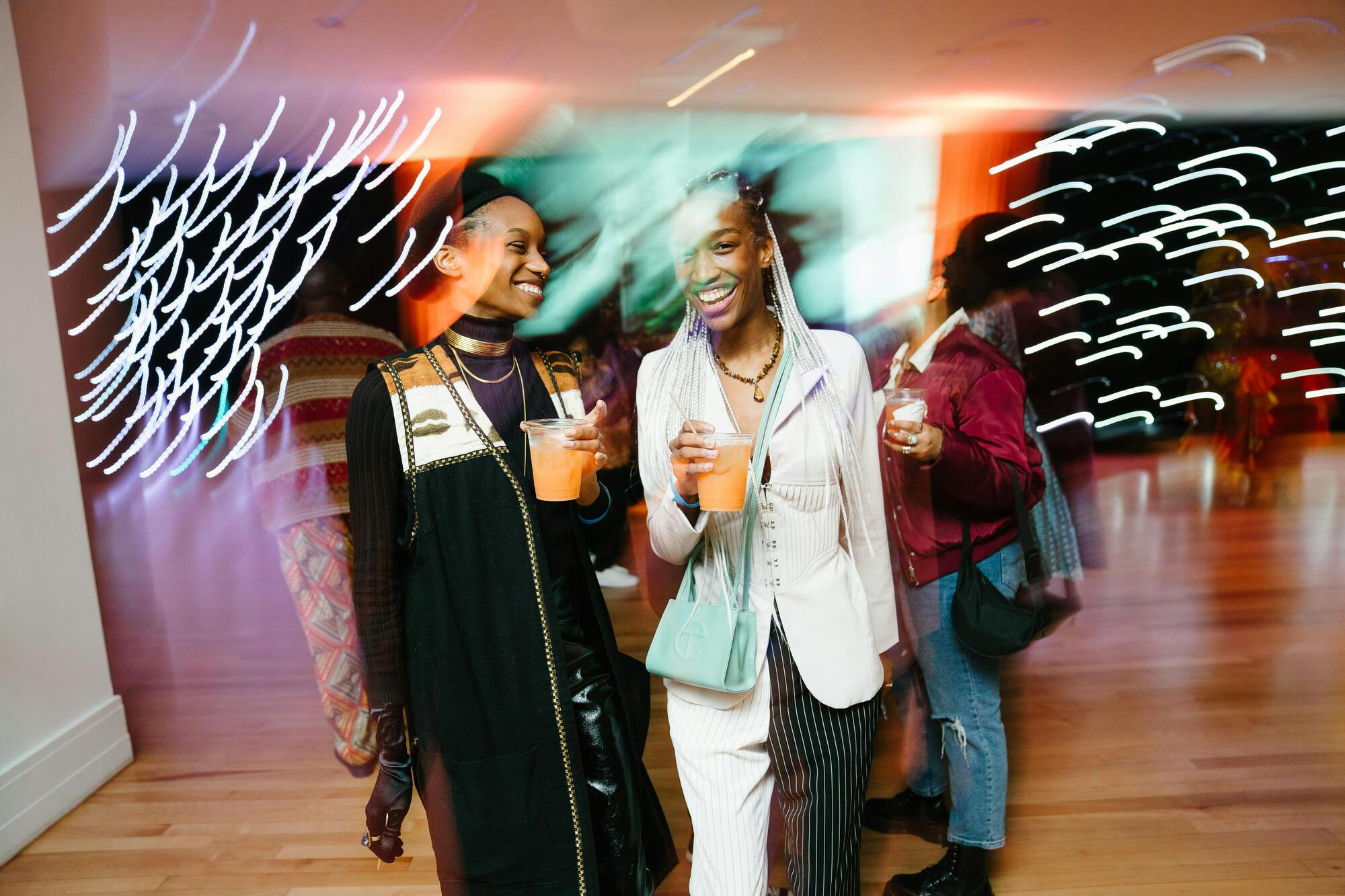 Two women holding beverages walk through a museum