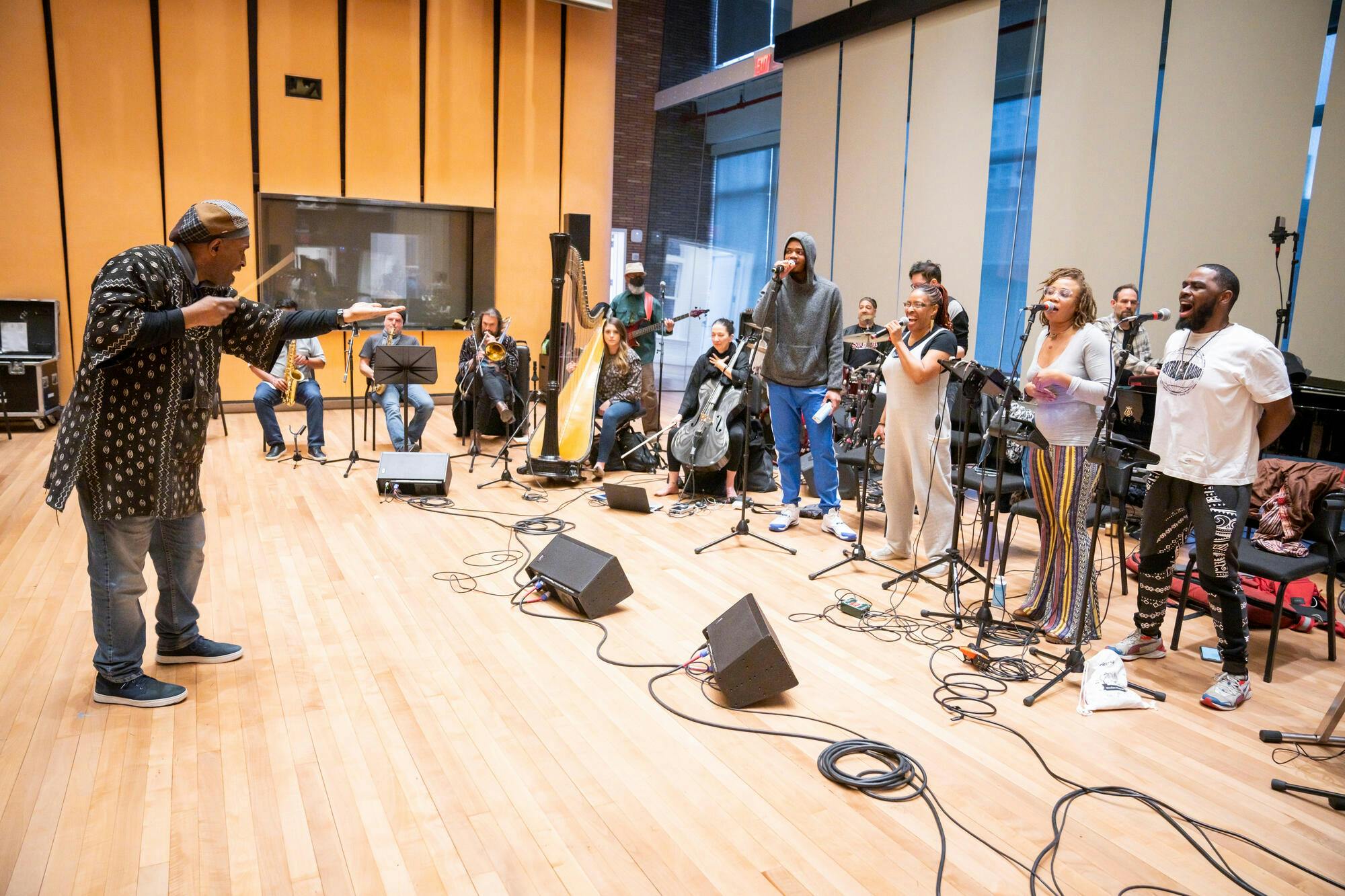 A man holding a baton conducts a quartet of singers in a studio classroom
