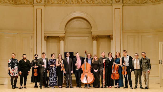 A group of musicians stand together in a line in Weill Recital Hall.