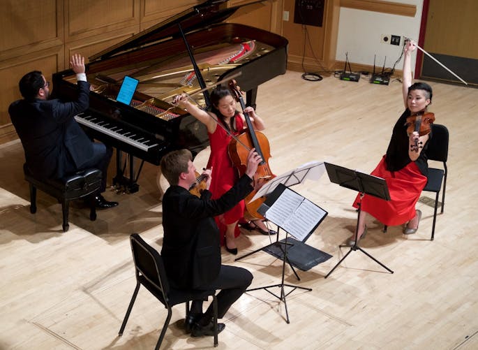 Three string musicians and a pianist perform together.