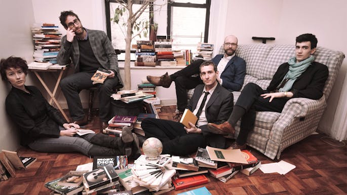 Musicians of Oracle Hysterical lounge in a small living room with books scattered around