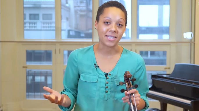 Dana Kelley holding her viola and speaking to the camera