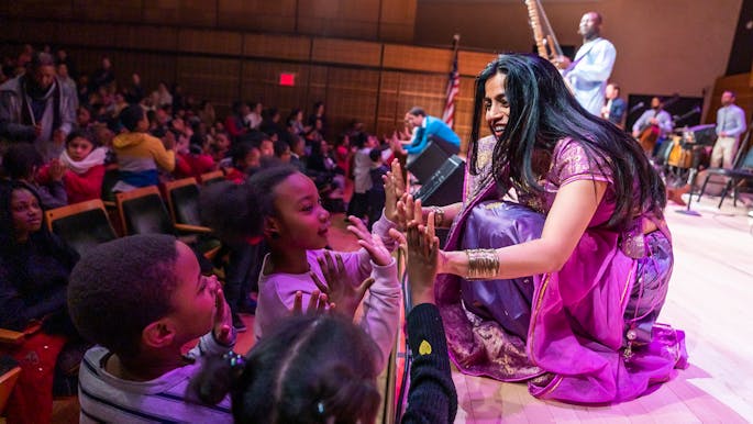 Three young children press their hands against Falu’s at the front of the stage in Zankel Hall.
