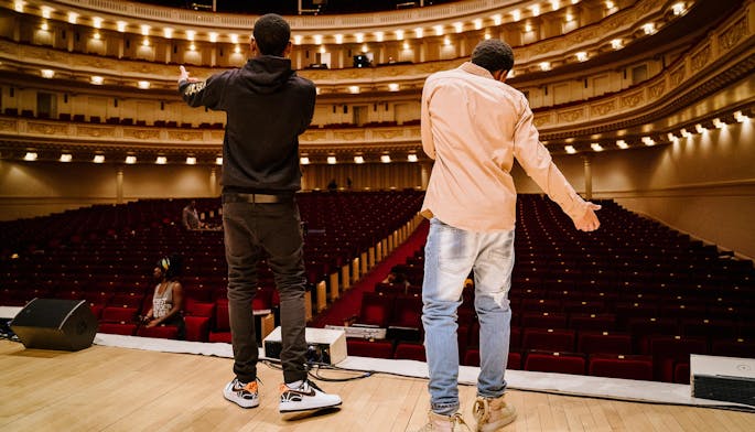 Back view of two young men on stage performing to the empty Carnegie Hall auditorium