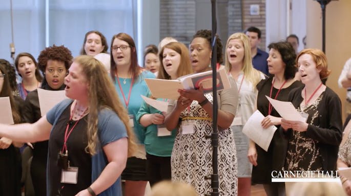 A presenter leads a choir of teachers