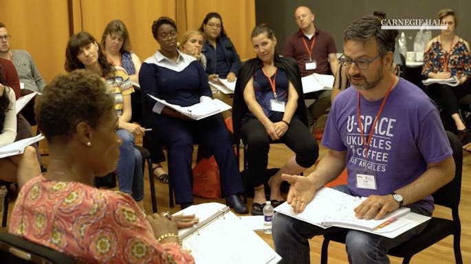 A teacher works one-on-one with a woman in a class for educators