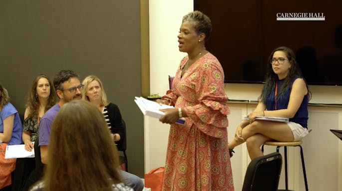 A woman speaks before a group of teachers in a workshop
