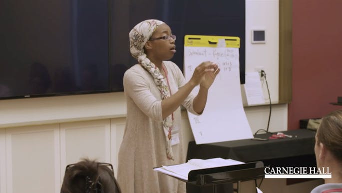 A teacher conducts a class of educators in a vocalization