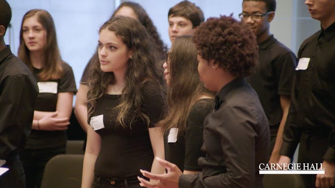 A group of young students sing together in a classroom