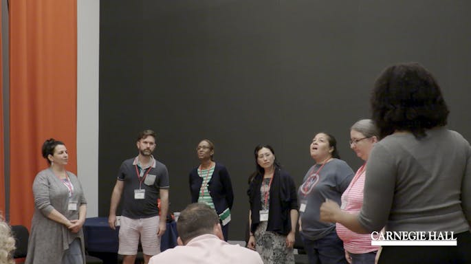 A circle of teachers sing together