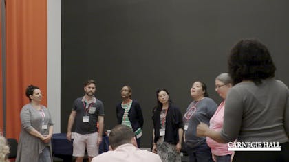 A circle of teachers sing together