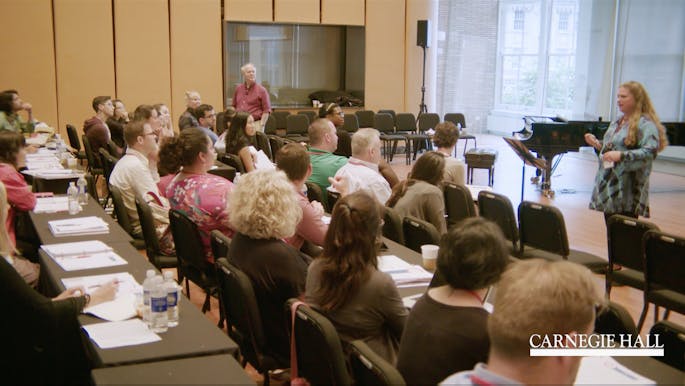 A presenter speaks before a group of teachers in a workshop