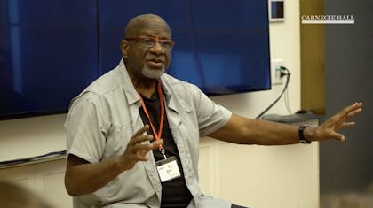 A man gestures as he speaks in a classroom