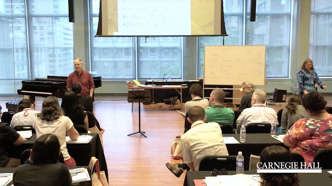 A presenter speaks before a class of teachers