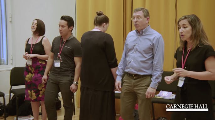 Tom Cabaniss and three teachers sing together as a woman plays keyboard