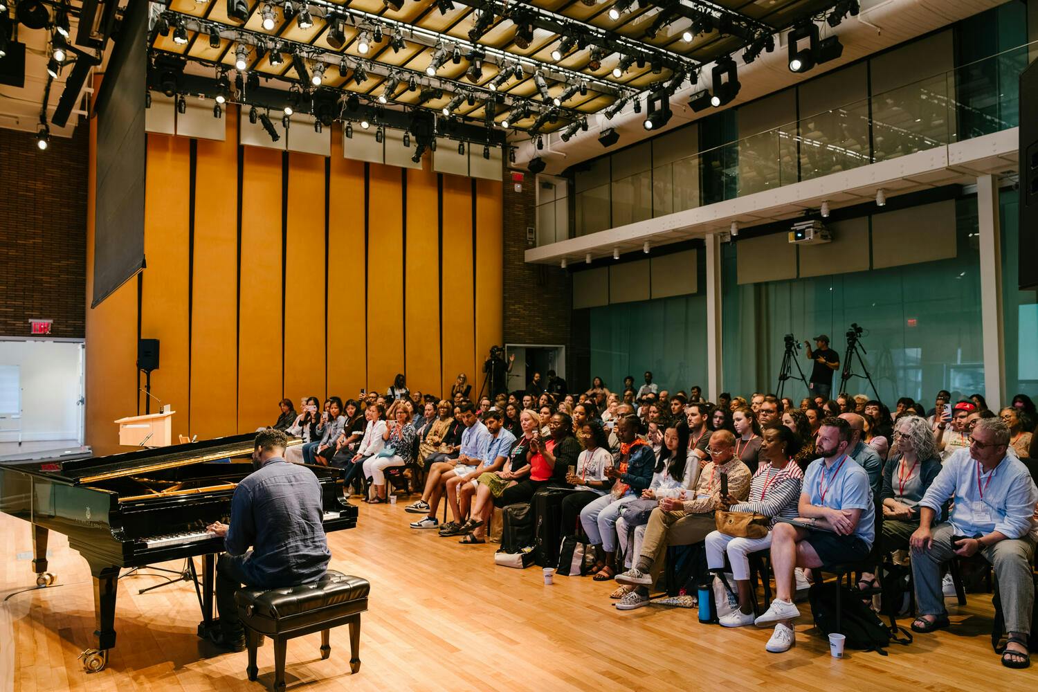 Workshop participants listen to Kris Bowers playing the piano in the Weill Music Room