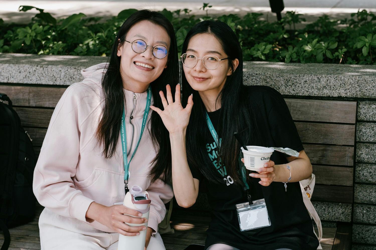 Two smiling women sit on a bench