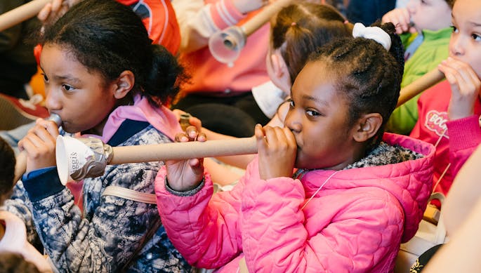 Children playing trumpets made from cardboard tubes and empty yogurt containers