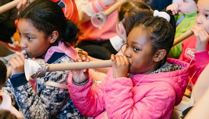 Children playing trumpets made from cardboard tubes and empty yogurt containers