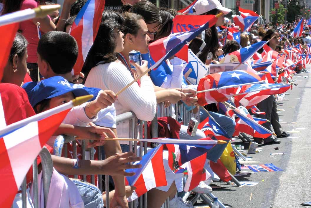 People wave flags along a parade route