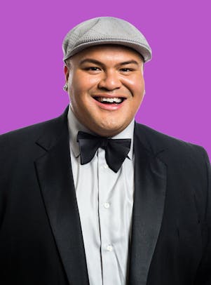 Kalani wearing a suit with bowtie and a cap against a purple background