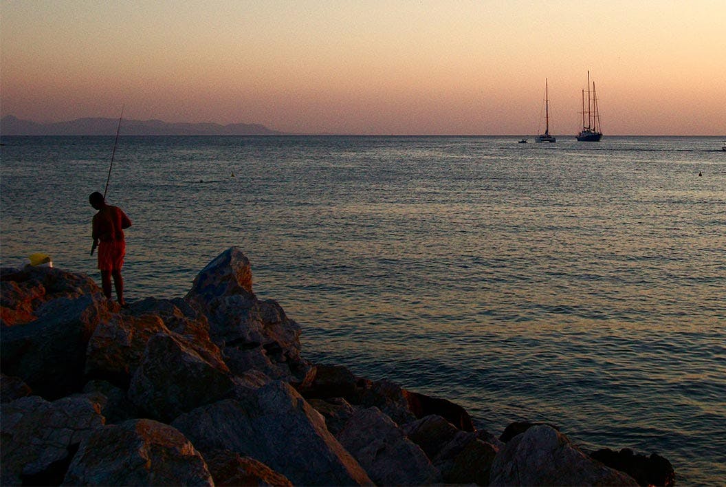 A man fishes at sunset