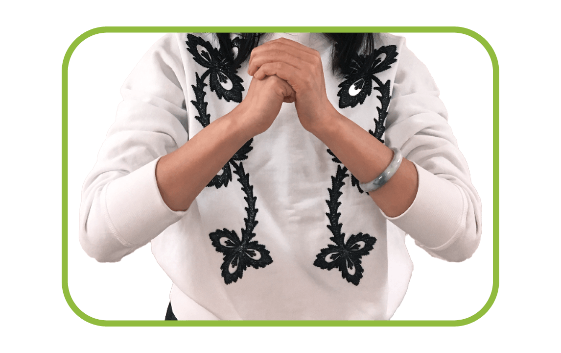 A woman stands with one hand cupped over the other, preparing to bow