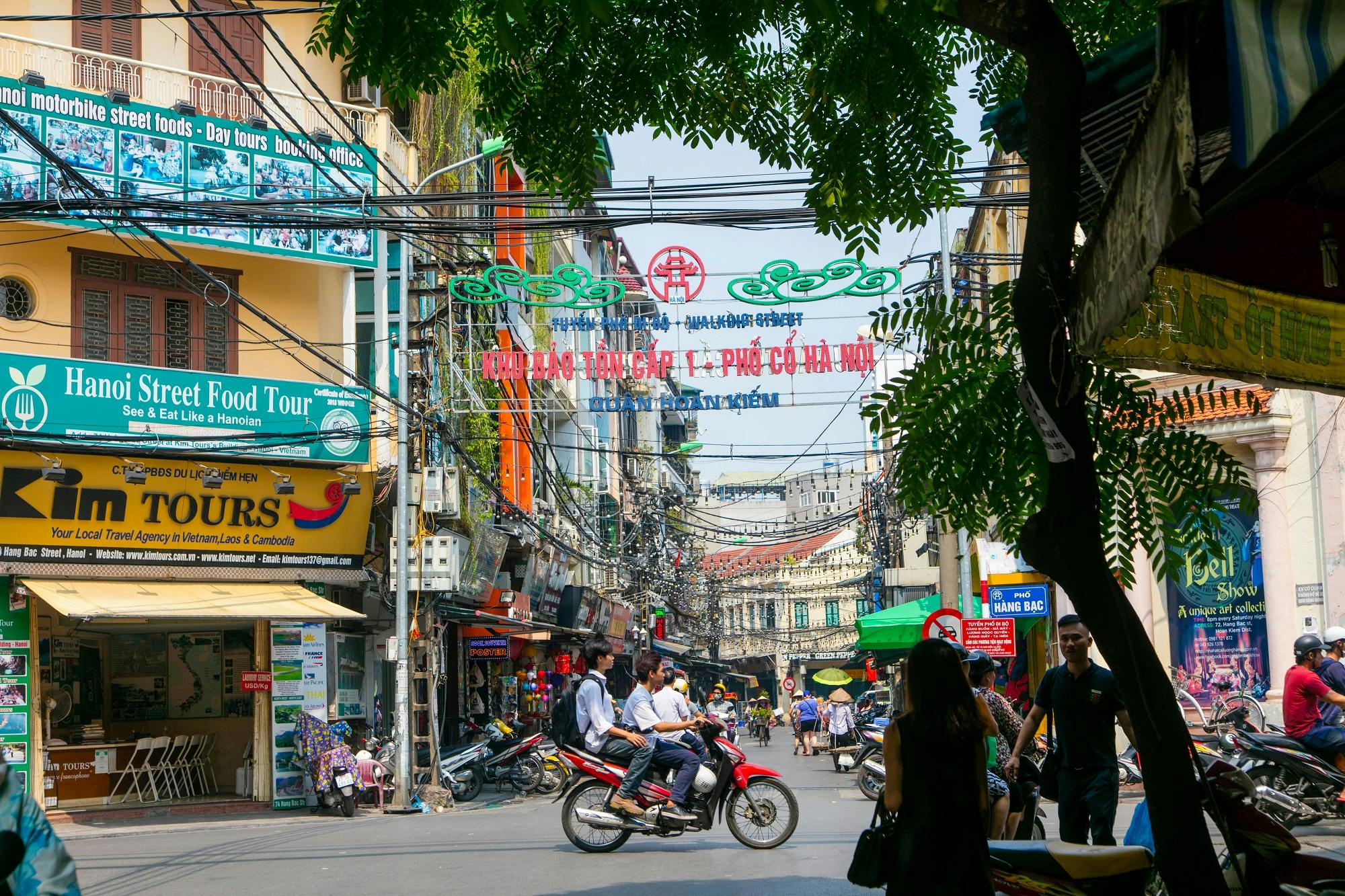 A motorbike with 3 boys on a street in Hanoi during the day
