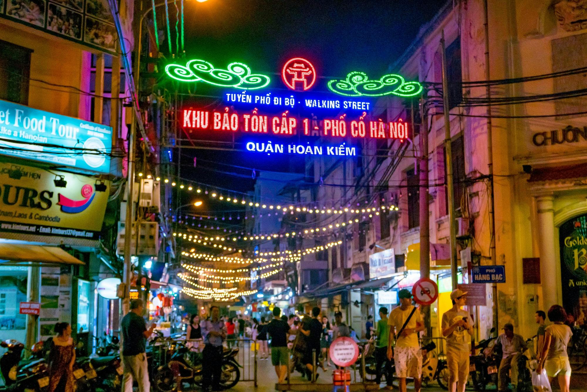 A street with lights strung overhead in Hanoi at night