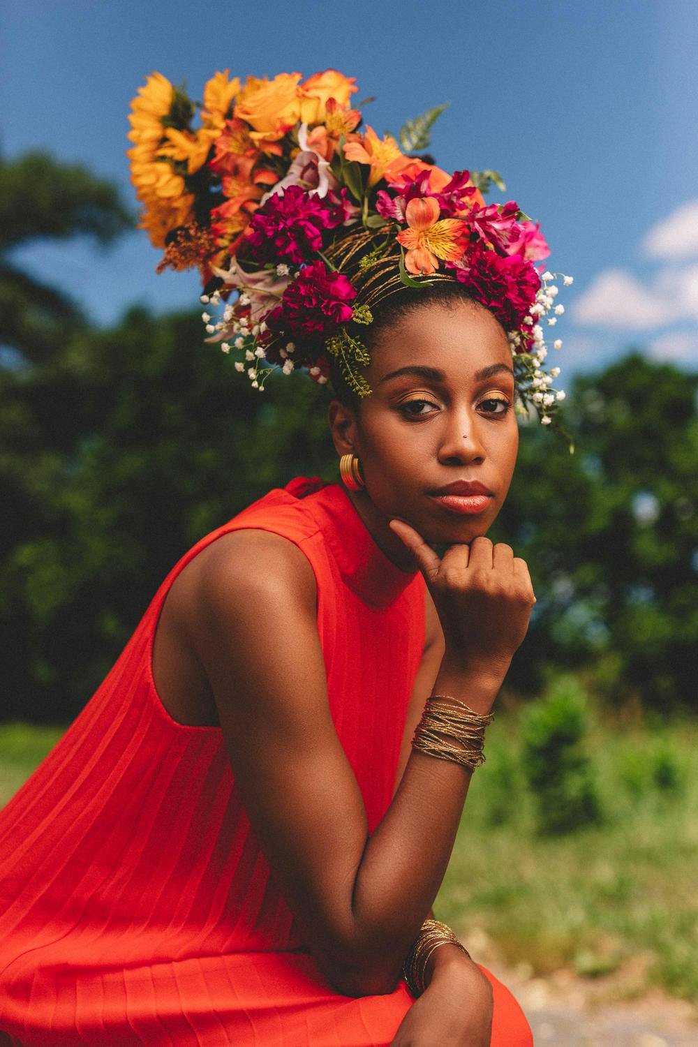 A woman wearing a flowered headdress rests her head in her hand