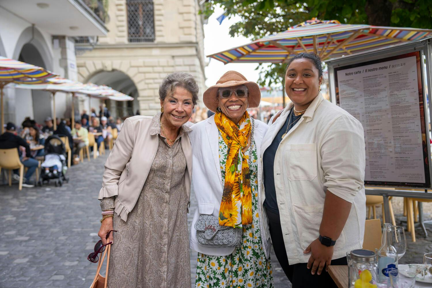 Smiling Dee Dee Bridgewater poses with two other women on a cobblestone street