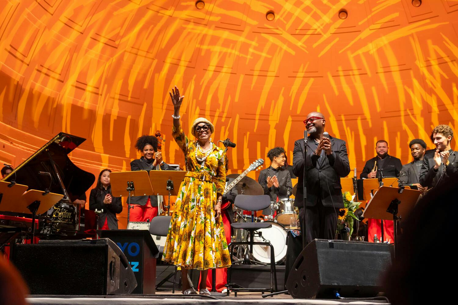 Dee Dee Bridgewater waves from stage as Sean Jones and the Jazz band applaud