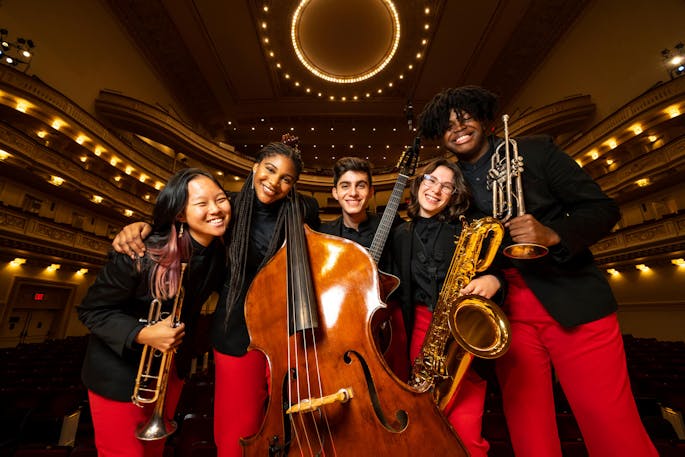 Young musicians of NYO Jazz pose with their instruments on stage at Carnegie Hall