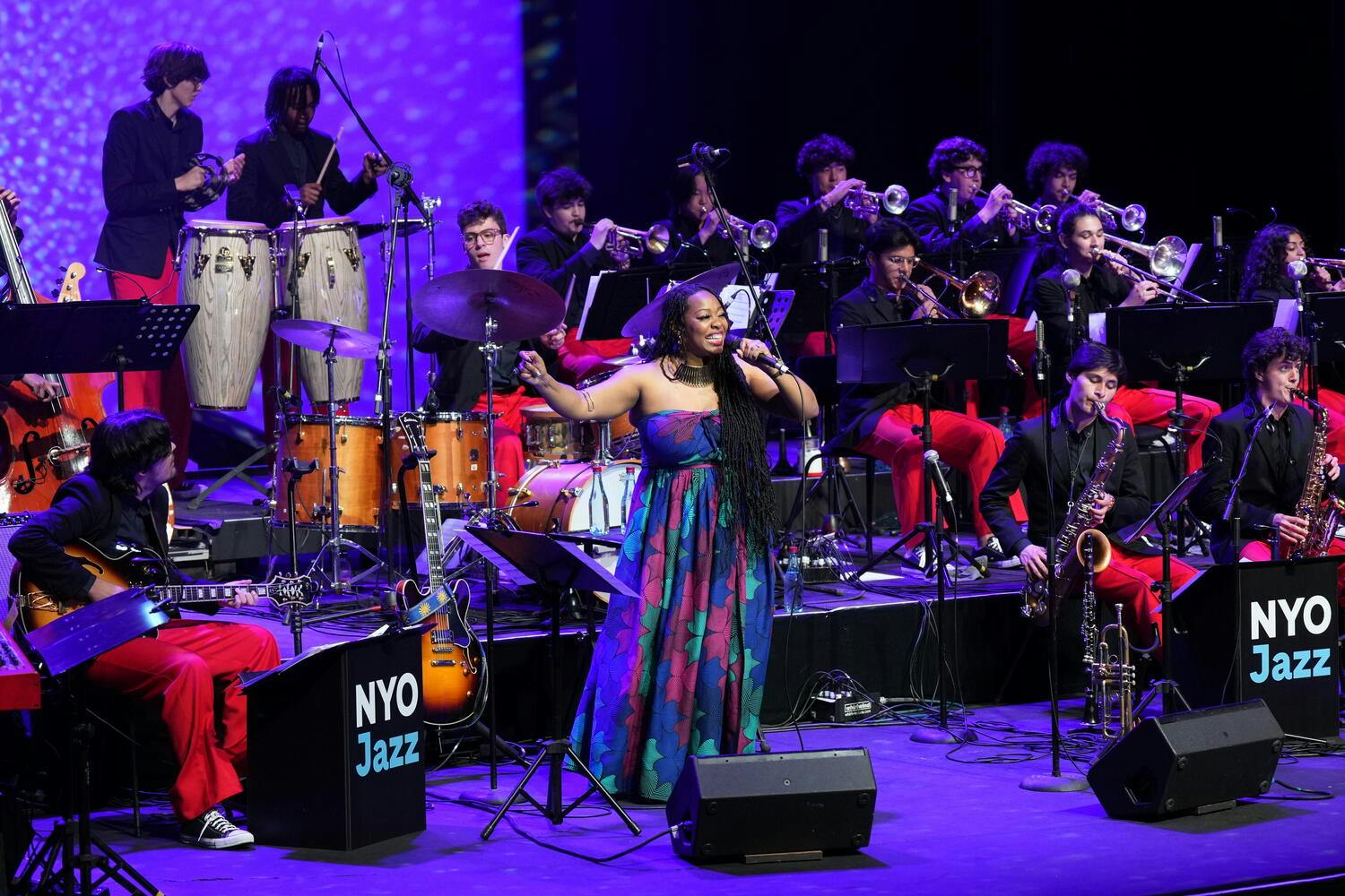 The NYO Jazz Band performs on stage as a woman sings