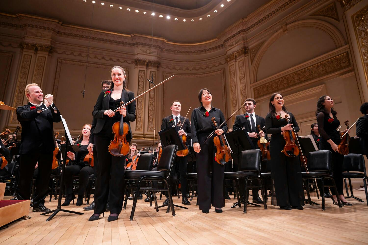 Yannick Nézet-Séguin applauds members of the string section on stage at Carnegie Hall