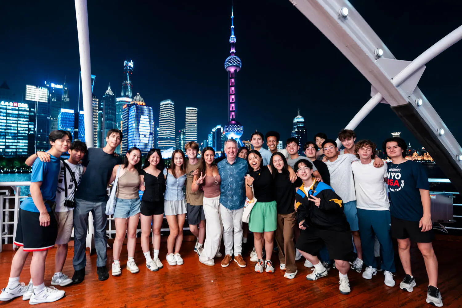 NYO-USA musicians pose together with night-time Beijing lit up behind them