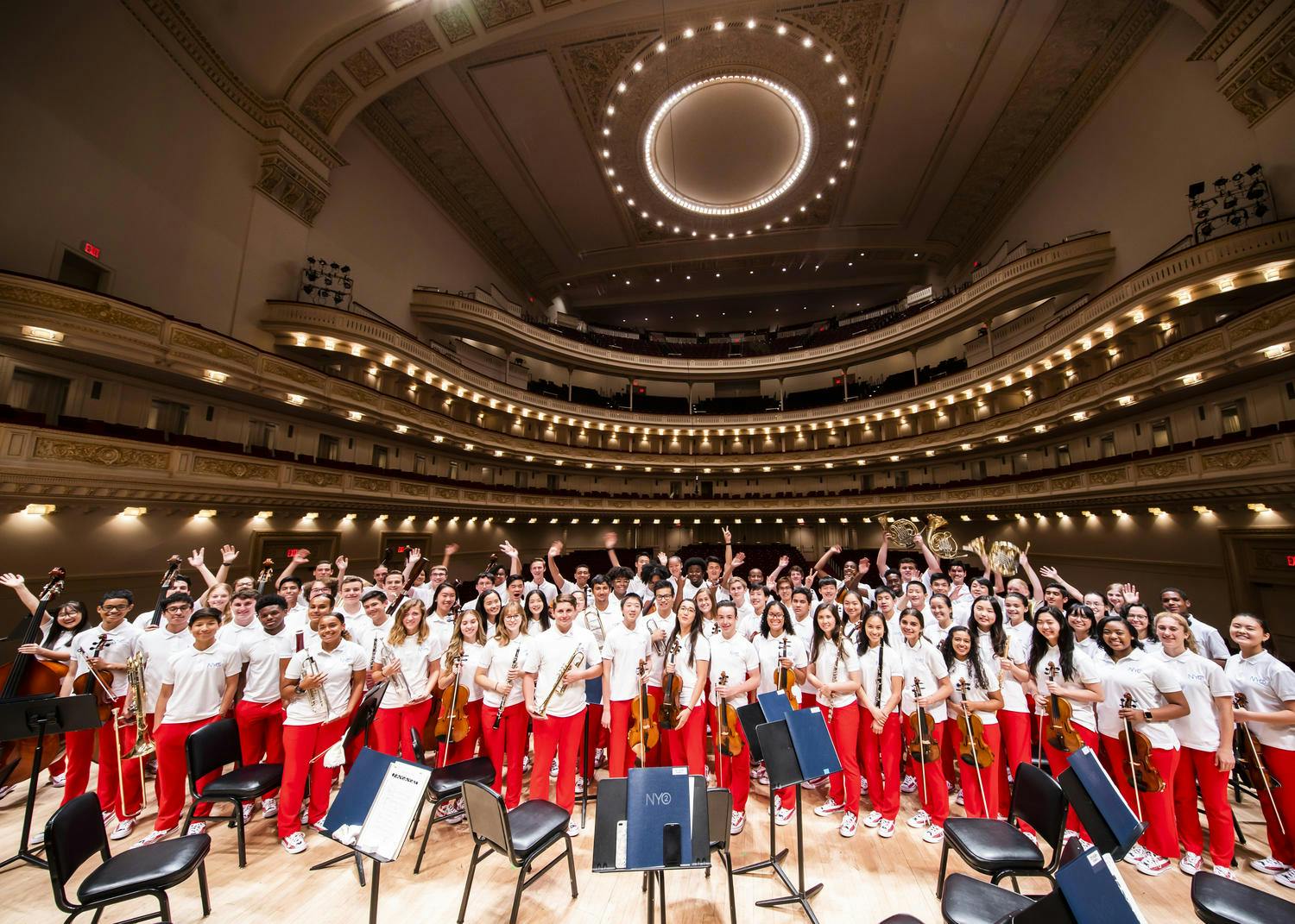 NYO2 musicians in red pants and white shirts on stage at Carnegie Hall