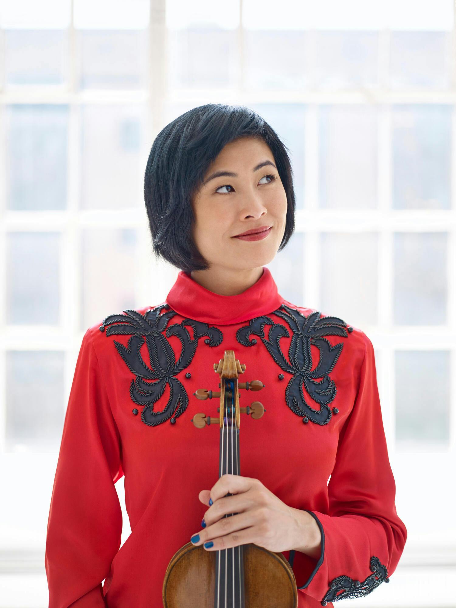 Jennifer Koh wearing a red blouse holding violin
