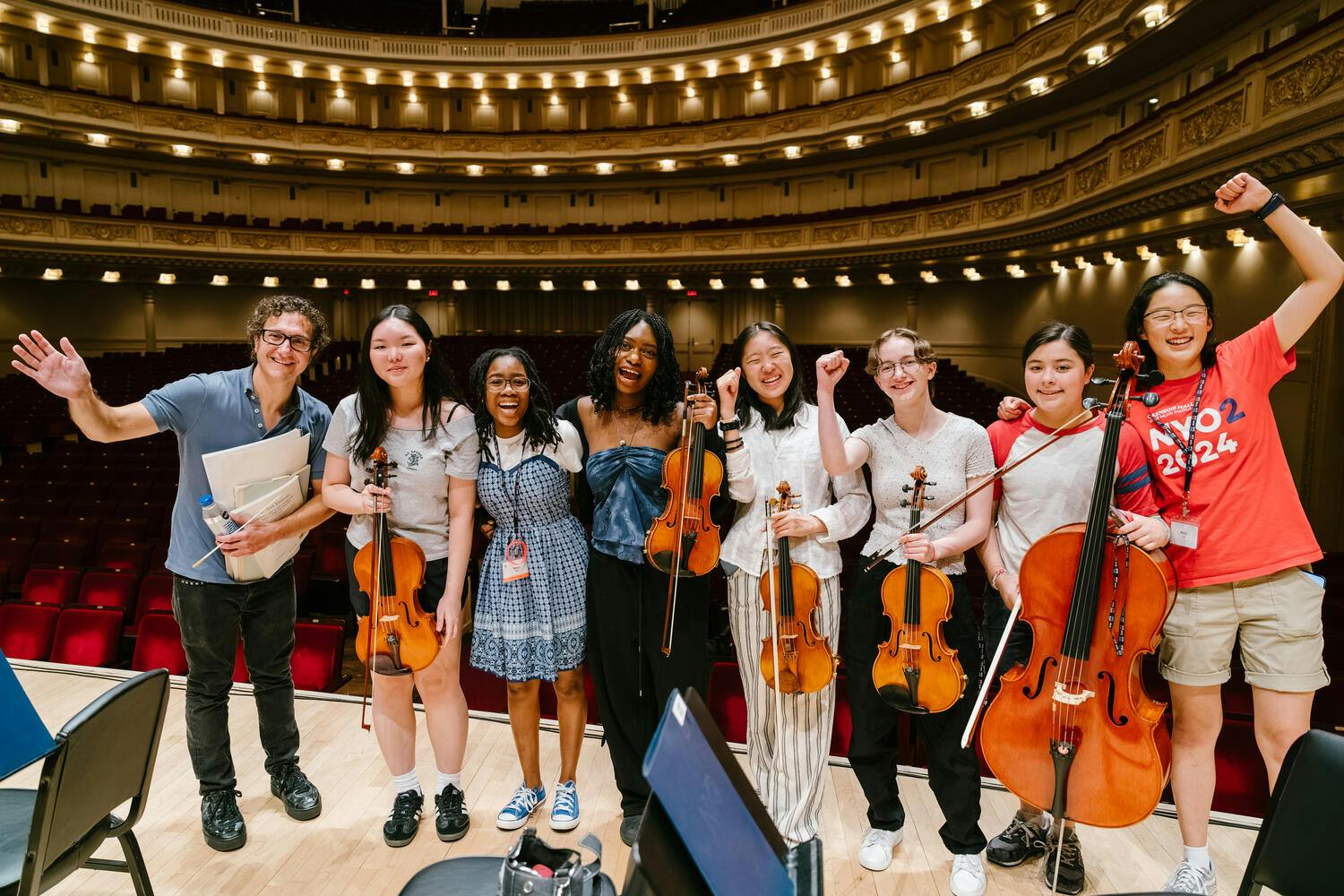 NYO2 musicians pose on stage at Carnegie Hall with conductor Teddy Abrams