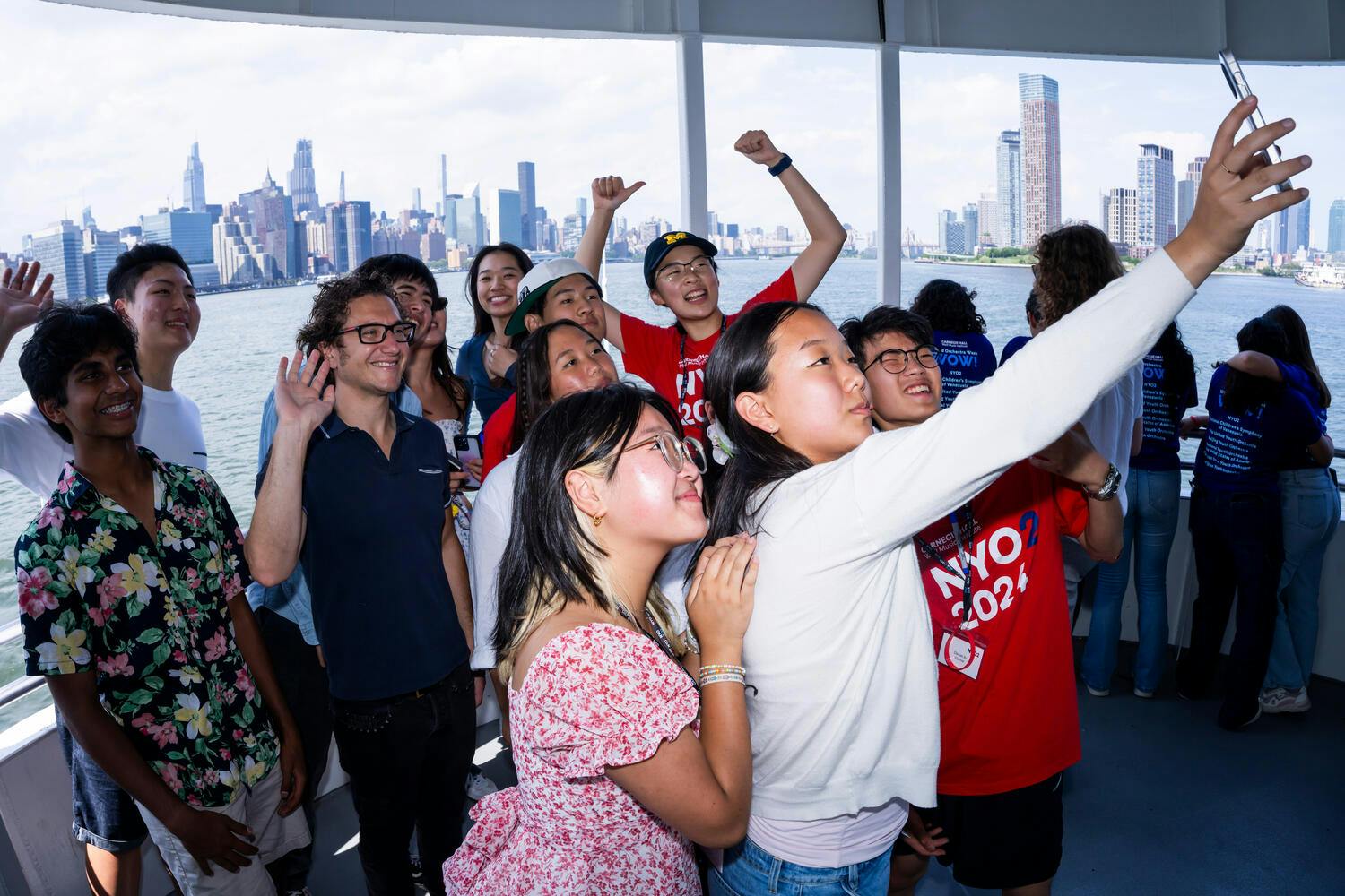 NYO2 musicians take a selfie on board a cruise, the Manhattan skyline in the background