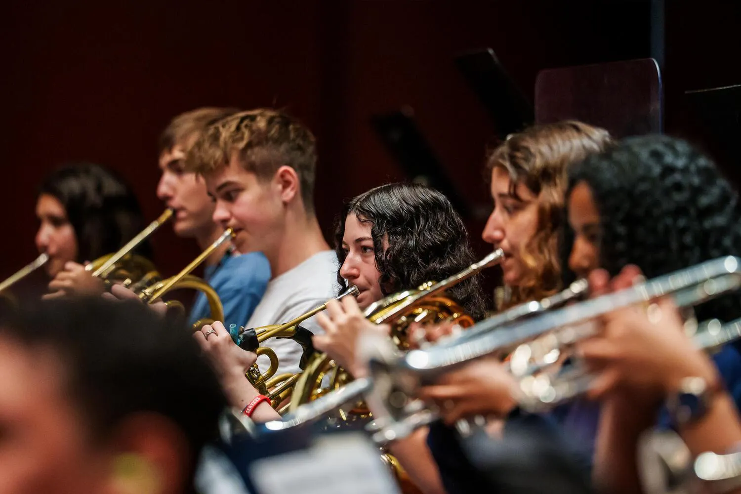 A row of NYO2 trumpet and horn players perform on stage