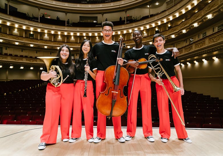 Young male and female musicians pose with their instruments on stage at Carnegie Hall