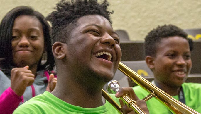 A boy holding a violin laughing
