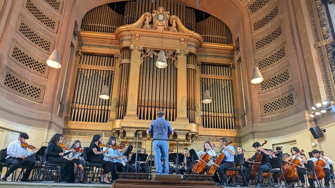 A youth orchestra rehearses together in a music hall.