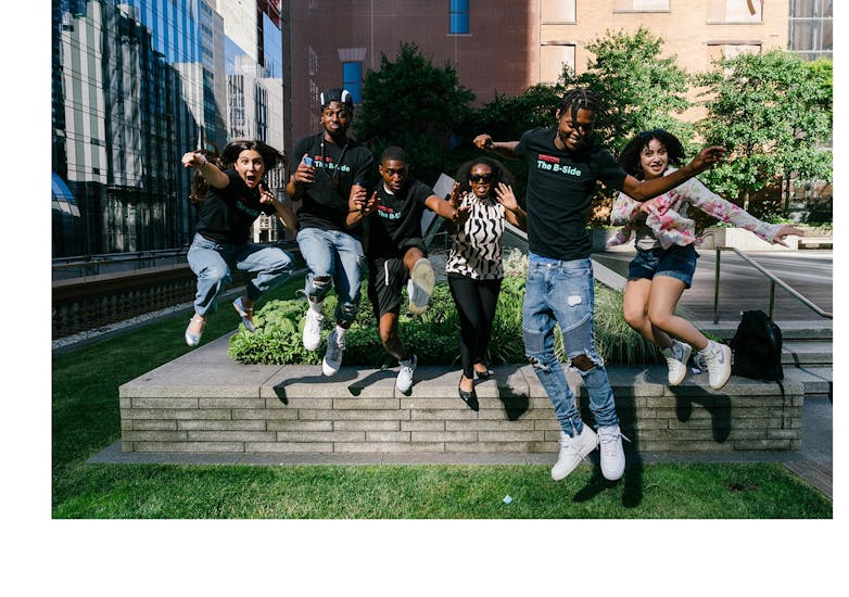 Young men and women wearing black t-shirts jump in the air