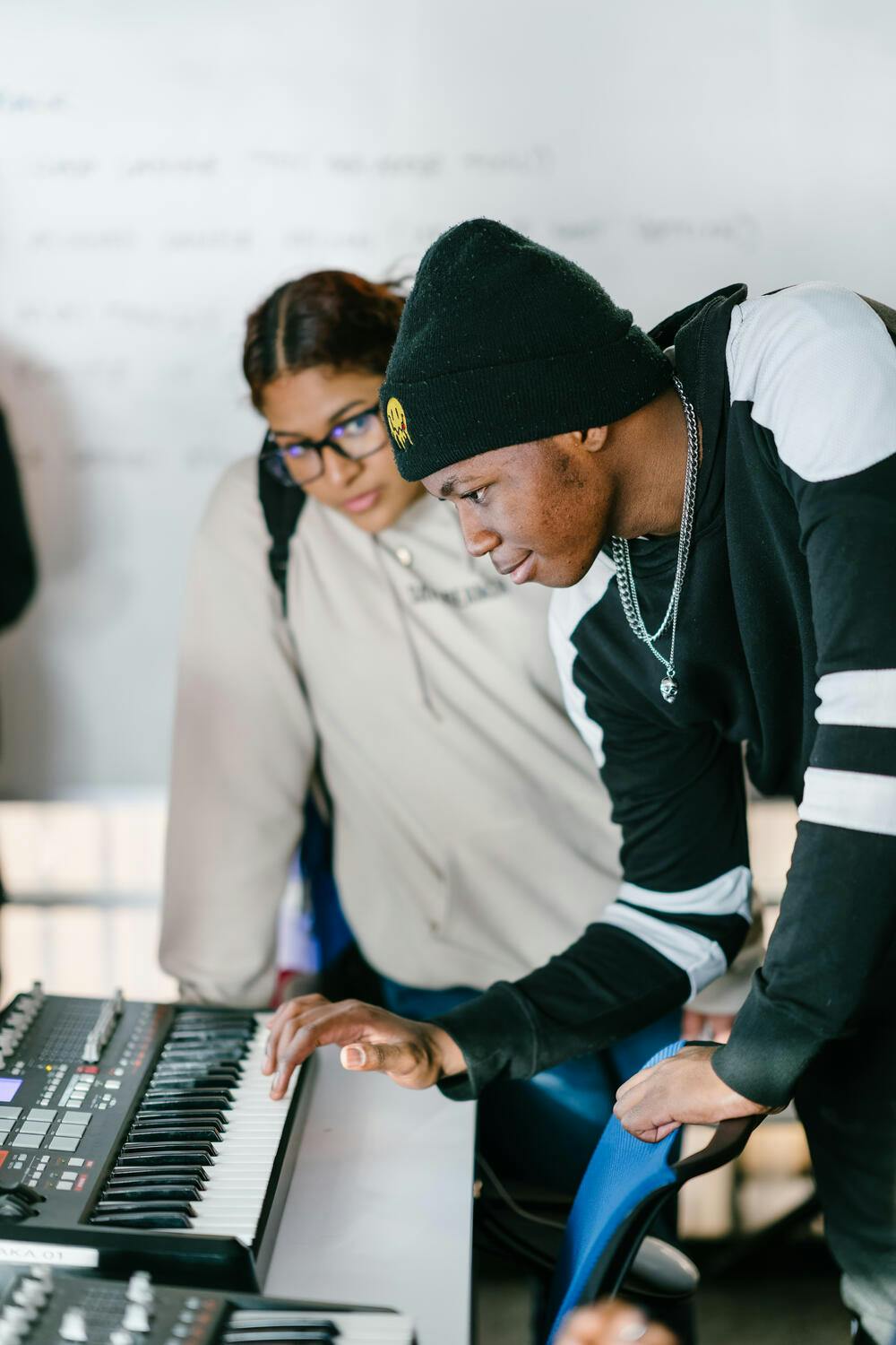 A young man and woman bent over a keyboard